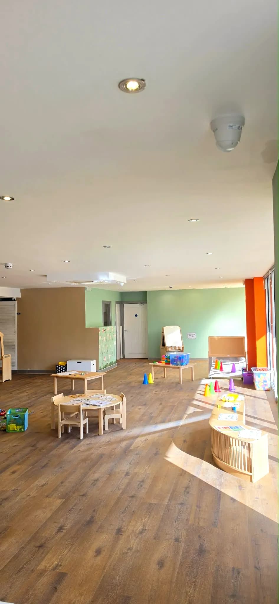 Lily's sunlit playroom with low tables, an easel and coloured cones by the windows